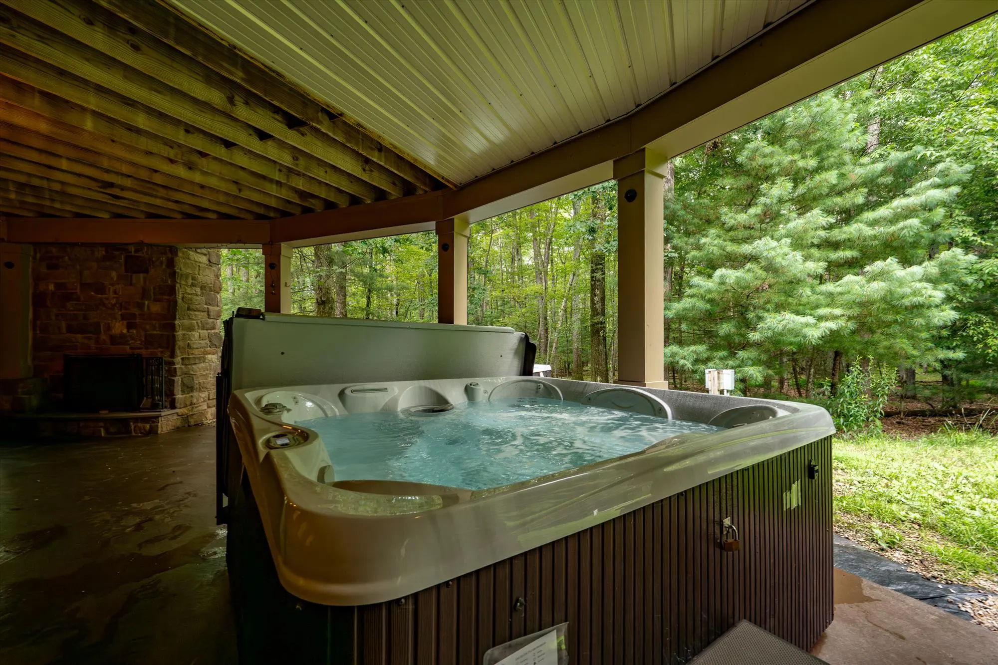 Outdoor hot tub on the lower patio surrounded by forest at Woodland Chalet