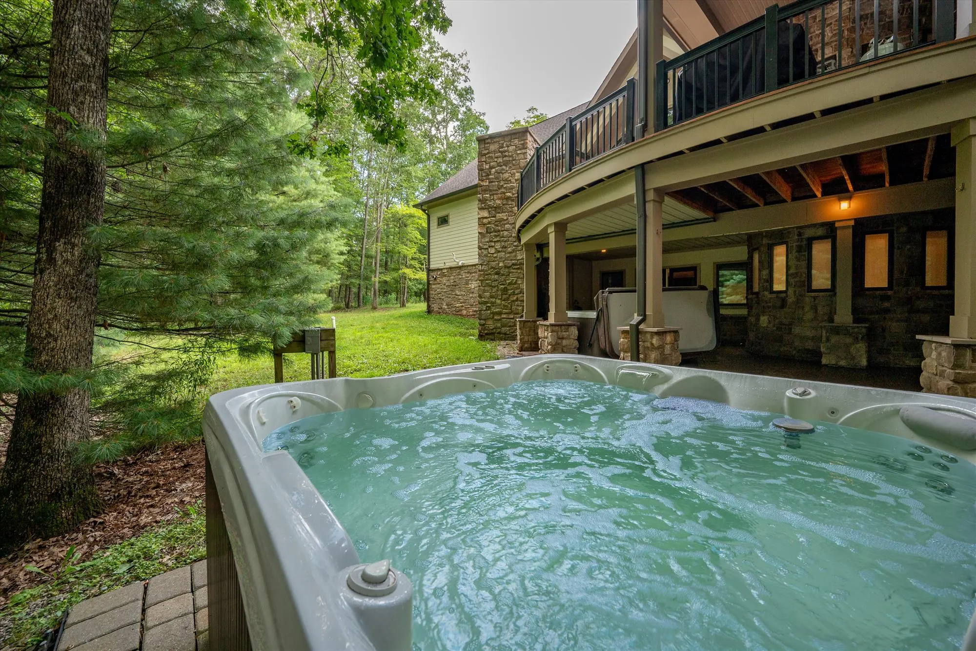 Close-up view of the second hot tub nestled among trees on the lower patio